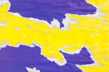 Dirty yellow and purple old crumpled, ripped and peeling paper posters on billboard with traces of...