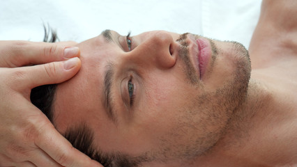 Close up of an young handsome man is receiving a facial massage and spa treatment for perfect skin in a luxury wellness center.