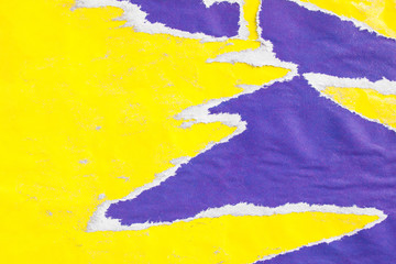 Yellow and purple crumpled, torn and peeling paper posters on billboard with dirty traces of glue...