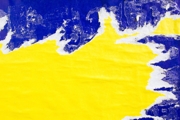 Yellow and blue old torn paper posters and placards with dirty traces of glue on billboard. Can be used for text.