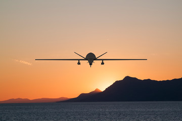 Fototapeta na wymiar Silhouette of spy drone flying over the sea (UAV) and on the background beautiful view of sun hiding behind surface of mountain
