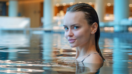 Portrait of an young smiling woman is enjoying and having relax in a indoor swimming pool in a...