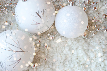 Decor for a happy Christmas and New year. Silver color. Christmas balls and beads on a white cozy blanket. happy winter holidays. Background for congratulations. White balls for Christmas tree decorat