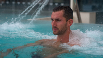 Portrait of an young man is enjoying and having relax in a whirlpool bath tube in a luxury wellness...
