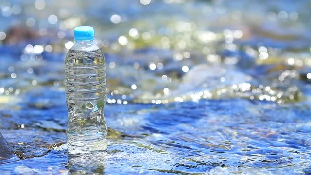 Pet bottle of mineral water with clean water stream in background.