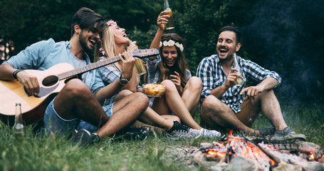 Obraz na płótnie Canvas Happy friends playing music and enjoying bonfire