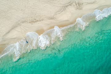 Aerial drone view of sandy white beach in summer with brilliant blue turquoise waters