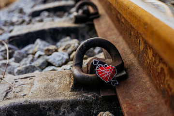 The red heart rests on old iron train tracks.