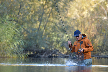 capture of a trout by a fly fisherman in autumn