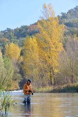 Fototapeta na wymiar fly fisherman in river in autumn