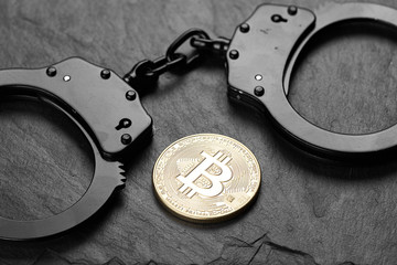 Bitcoin and black handcuffs on stone background
