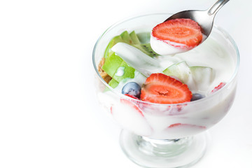 Bowl of homemade granola with yogurt and fresh berries: strawberry, kiwi and blueberry on white  background  from top view. Half the strawberry berries lie on a spoon. Copy space