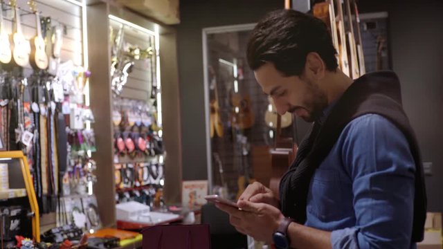 An upwardly mobile Middle Eastern man using a mobile phone to scan the QR Code for verification, authentication and secure payment transaction at the point of sale terminal in a retail store