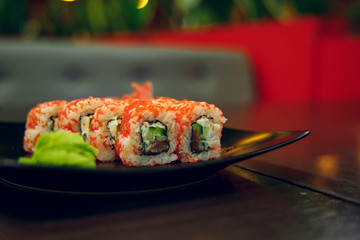 soft focus sushi rolls on black plate in twilight restaurant interior food photography concept 