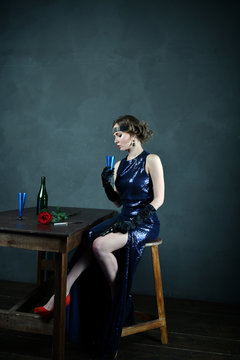 girl in evening blue dress with a blue glass