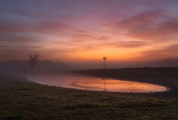 Fototapeta na wymiar Red skies at dawn with light mist across rural farmlands