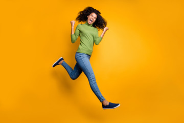 Fototapeta na wymiar Turned full length body size photo of cheerful positive emotional curly wavy crazy fashion girl in jeans denim green sweater isolated running jumping vivid color background