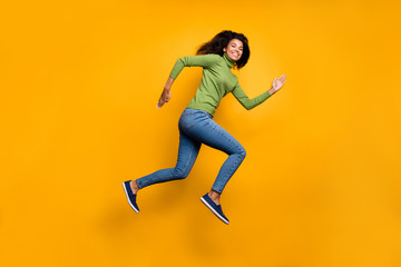 Full length body size side profile photo of cheerful positive aspiring toothy running jumping beaming girl in green sweater footwear curly isolated vivid color background