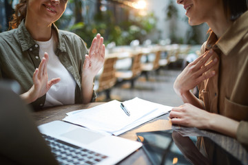 Close up of unrecognizable young woman gesturing actively during business meeting in cafe with...