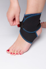 fixing a bandage to female foot to support the ankle