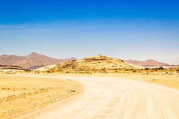 Fototapeta na wymiar Gravel road that leads to the granite mountain Blutkuppe, Naukluft Park, Namibia, Africa