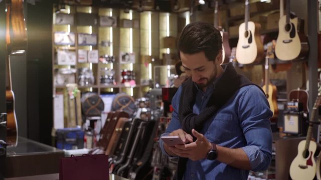 An upwardly mobile Middle Eastern man using a mobile phone to scan the QR Code for verification, authentication and secure payment transaction at the point of sale terminal in a retail store