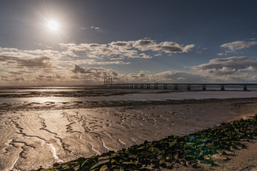 The setting sun over the Prince of Wales Bridge, seen from Severn Beach, South Gloucestershire,...