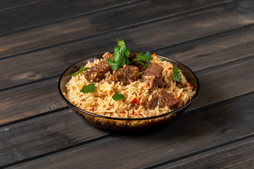 Oriental cuisine. National Uzbek pilaf with meat on a wooden table. Top view, copy space.