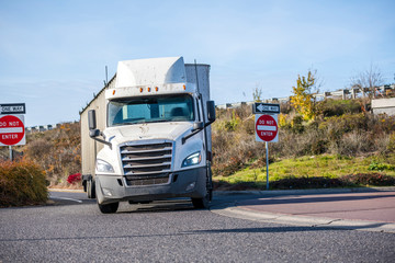 Day cab big rig semi truck with roof spoiler transporting cargo in bulk semi trailer turning on the...
