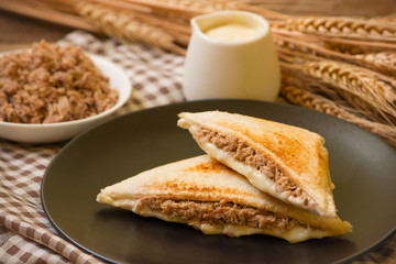 Sandwich stuffed with salad sauce and dried Tuna in black dish on wooden table.