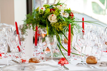 Wedding arrangement for dinner in white with beautiful flowers and long red candles
