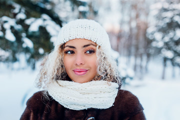 Close-up portrait of beautiful young afro american woman in winter forest. Wintertime