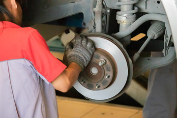 The mechanic is cleaning the front wheel brake set of the car before changing to a new wheel.