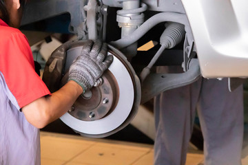 The mechanic is cleaning the front wheel brake set of the car before changing to a new wheel.