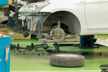 Car brakes with wheels that have been removed and parts removed for repair. There are rubber shock absorbers in the repair area of the garage.