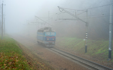 The locomotive is moving in the fog. Electric locomotive without cars. Autumn fog.