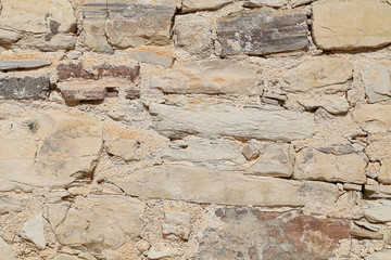 Background, old wall of stacked stone blocks of different shapes.