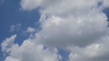 Ant's eye view of fat white clouds moving in strong wind with blue sky background.