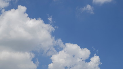 Ant's eye view of fat white clouds moving in strong wind with blue sky background.