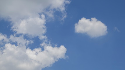 Ant's eye view of fat white clouds moving in strong wind with blue sky background.