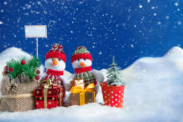 Snowman in a snowdrift with gifts for Christmas and New year