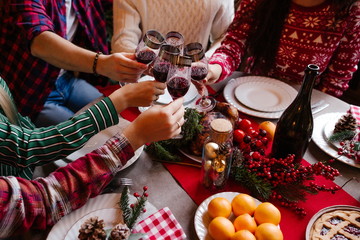 Friends sitting at a festive table celebrate the new year clinking glasses