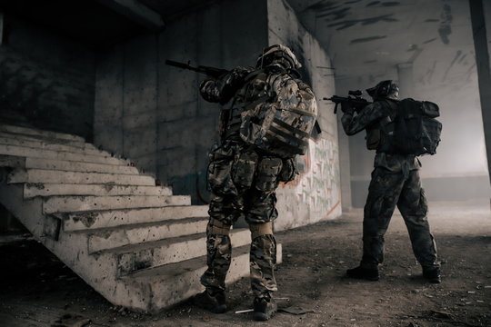 Two military soldiers in camouflage with assault rifles storm the building