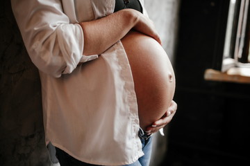 Pregnant girl in the white shirt holding the belly with the baby