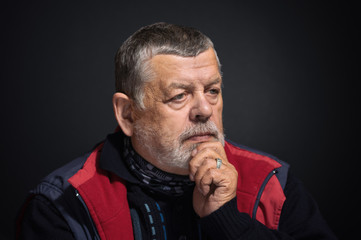 Nice portrait of Caucasian bearded senior man thinking about life problems in darkness