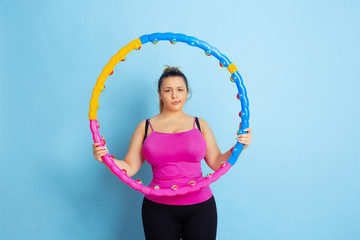 Young caucasian plus size female model's training on blue background. Concept of sport, human...