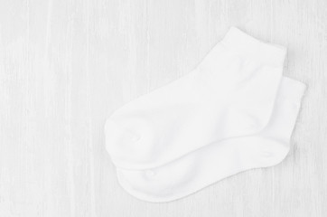 Pair blank white medium socks flat lay on white wood board, side view - mock up for design, print,...