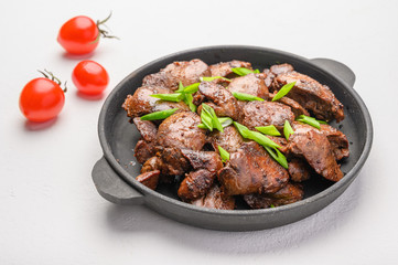 Homemade chicken liver fried with soy sauce, tomatoes, onions and spices on light background