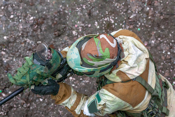 A man in a protective mask, a participant in a paintball game is in the process of playing, top view