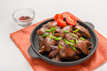 Homemade chicken liver fried with soy sauce, tomatoes, onions and spices on light background. Close up